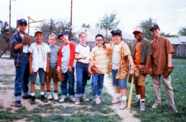 A group of boys stand on a deteriorating grass field in old baseball gear