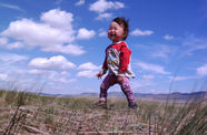 A smiling baby stands in a field