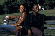 Man and woman sit back to back laughing on park bench