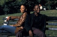 Man and woman sit back to back laughing on park bench