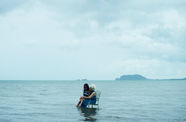 woman and child sit in lawn chair floating in ocean