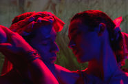 Two people look at each other intimately in blue/red light