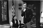 Woman looks up at man in black and white government office