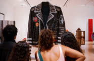 Gallery visitors looking at an Ishi Glinsky artwork, a massive leather jacket