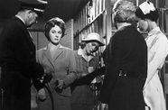 A woman stands in a prison, surrounded by four people
