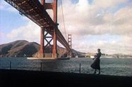 A woman stands at the waterfront in front of the Golden Gate Bridge