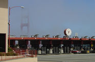 A toll booth with the Golden Gate Bridge in the distance, shrouded by fog