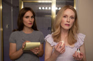 Natalie Portman and Julianne Moore stand in a bathroom, Moore putting on makeup, Portman taking notes