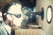 A man looking through a porthole, wearing goggles