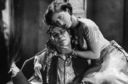 A woman cradles the dead of a man who holds a lit cigarette between his toes