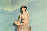 A Korean man stripped to his underwear sits cross-legged on a tree stump