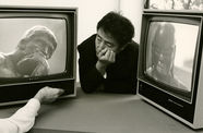 Nam June Paik rests between two TV monitors
