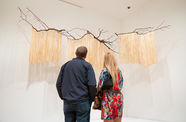 Two visitors look up at a hanging artwork