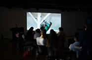 A crowd watches a video