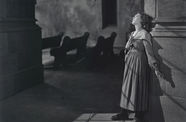 Mary Pickford leans against a wall, looking up at the light