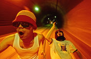 Two men in sunglasses run through a tunnel