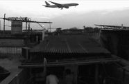 Black and white image of an airplane flying over a village
