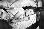 Joan Fontaine laying in a bed