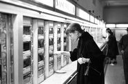 Black and white photo of Audrey Hepburn inspecting items in an automat