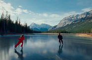 Two figures skate on a frozen lake