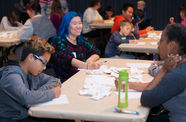 Smiling young teens sit at a table and write