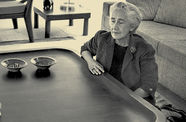 Clara Porset sits on the floor next to a large wooden coffee table