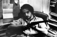 still from ice of a man sitting pointing a shotgun