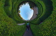 Still of a figure walking in a garden, with the image distorted into a 