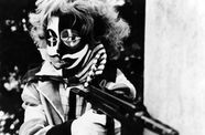 still from third generation of woman wearing mask and holding gun