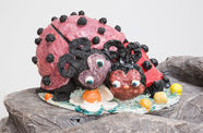Sculpture of two ladybugs with noses and large eyes laying on top of each other