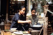mother and daughter cooking outside