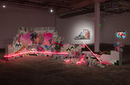 Installation featuring a crumbling wall of cinderblocks with handpainted images and pink neon lights
