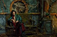 Oscar Isaac as Dr. Frankenstein, dressed in lush robes, sits pensively on a bench overgrown with weeds