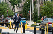 A man in a blue suit runs down a city street