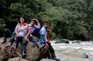 Berta Cáceres and four young men sit on a boulder in a river