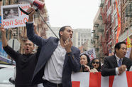 A man with a loudspeaker stands at the front of a large protest