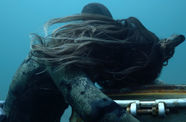 Underwater scene of a diver holding onto a sunken barrel