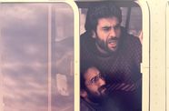 Two men lean out of an open train window
