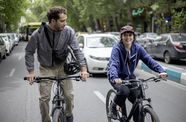 A young man and woman bike down a city street
