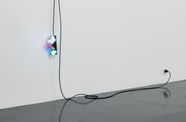 A black extension cord hangs from a wall, with three butterfly nightlights plugged into it