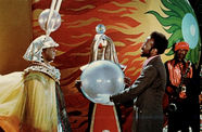 Sun Ra, in an elaborate headdress, stands with a man holding a large orb in his white-gloved hands