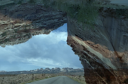 A onpen road on a barren landscape framed by canyons.