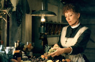 A woman in an apron handles a bunch of grapes