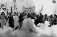 People protest in a street, surrounded by white smoke