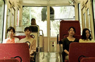 Four women sit in two pairs on the benches of a funicular