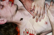 Crumpled image of a pale, topless man laying prone with two hands placed on their chest