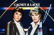 Two women with short hair stand in front of a graphic background reading CAGNEY & LACEY