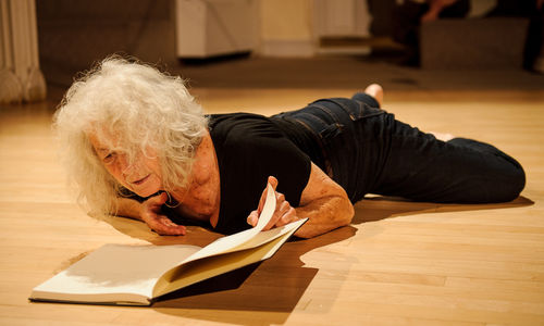 A woman lies on the ground, looking into an open book