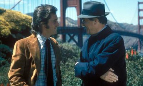Two men talk with the Golden Gate bridge behind them