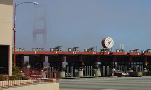 A toll booth with the Golden Gate Bridge in the distance, shrouded by fog